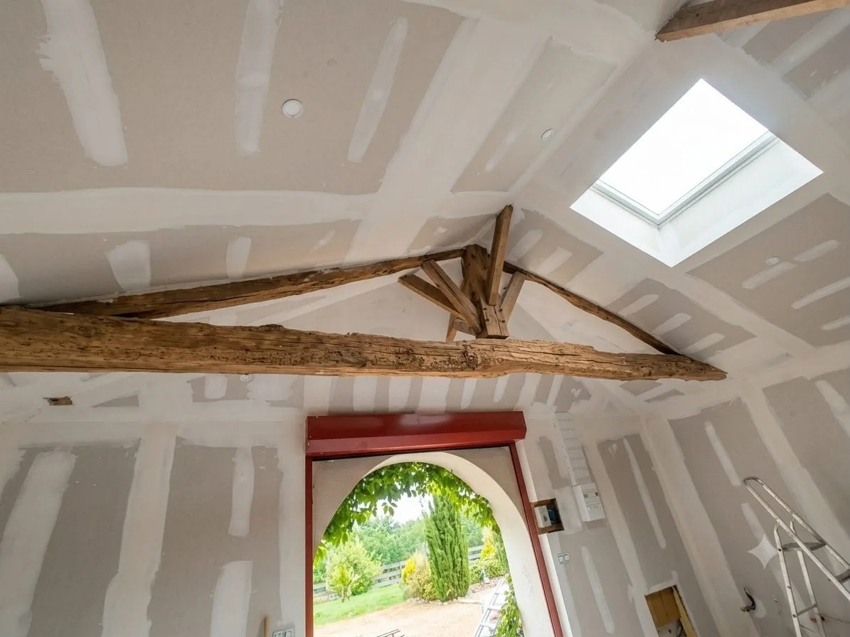 Plafond en plaques de plâtre entre poutres anciennes avec fenêtre de toit — rénovation près de Tonneins (47)